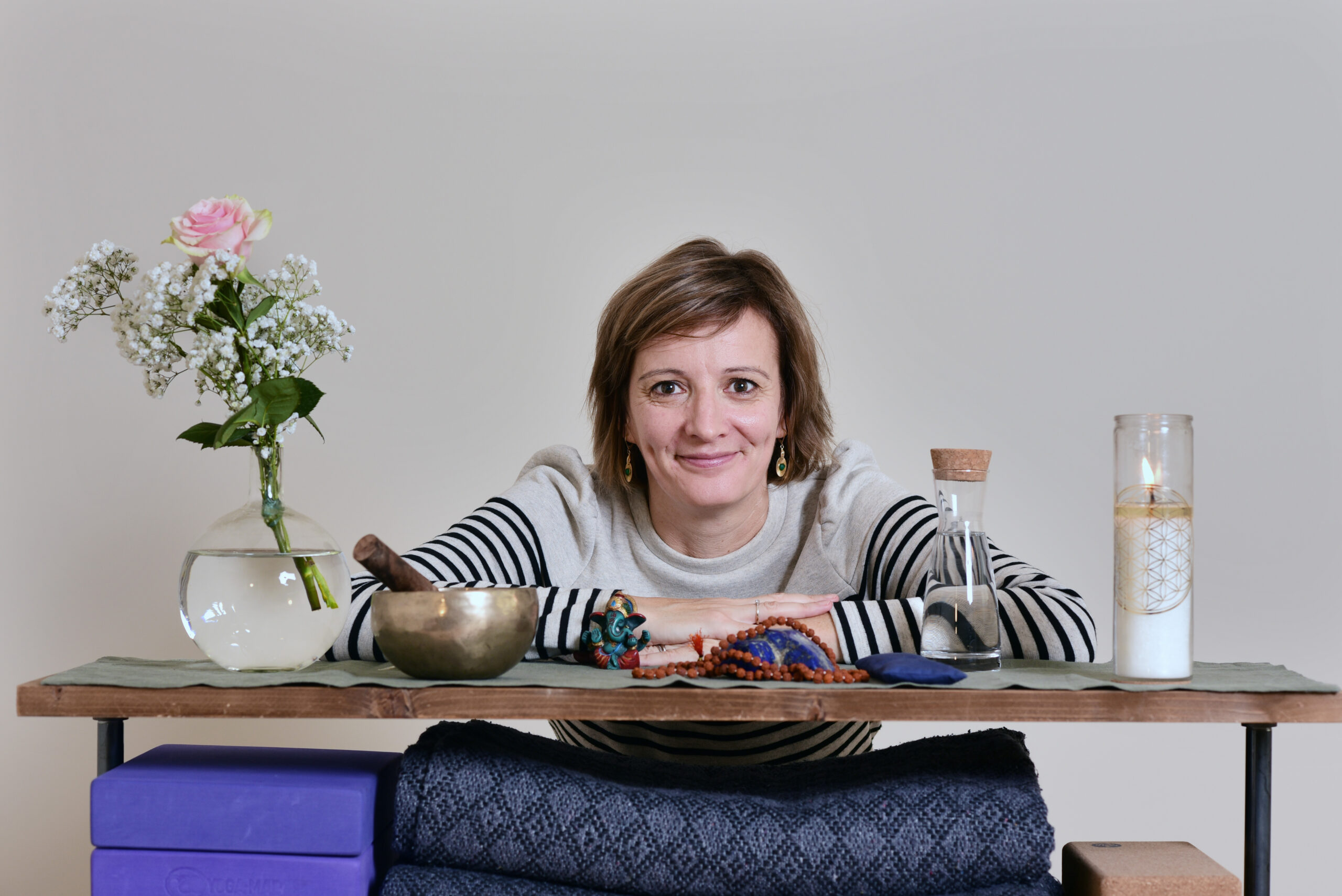 Audrey Favreau behind a table with flowers, a singing bowl and a candle