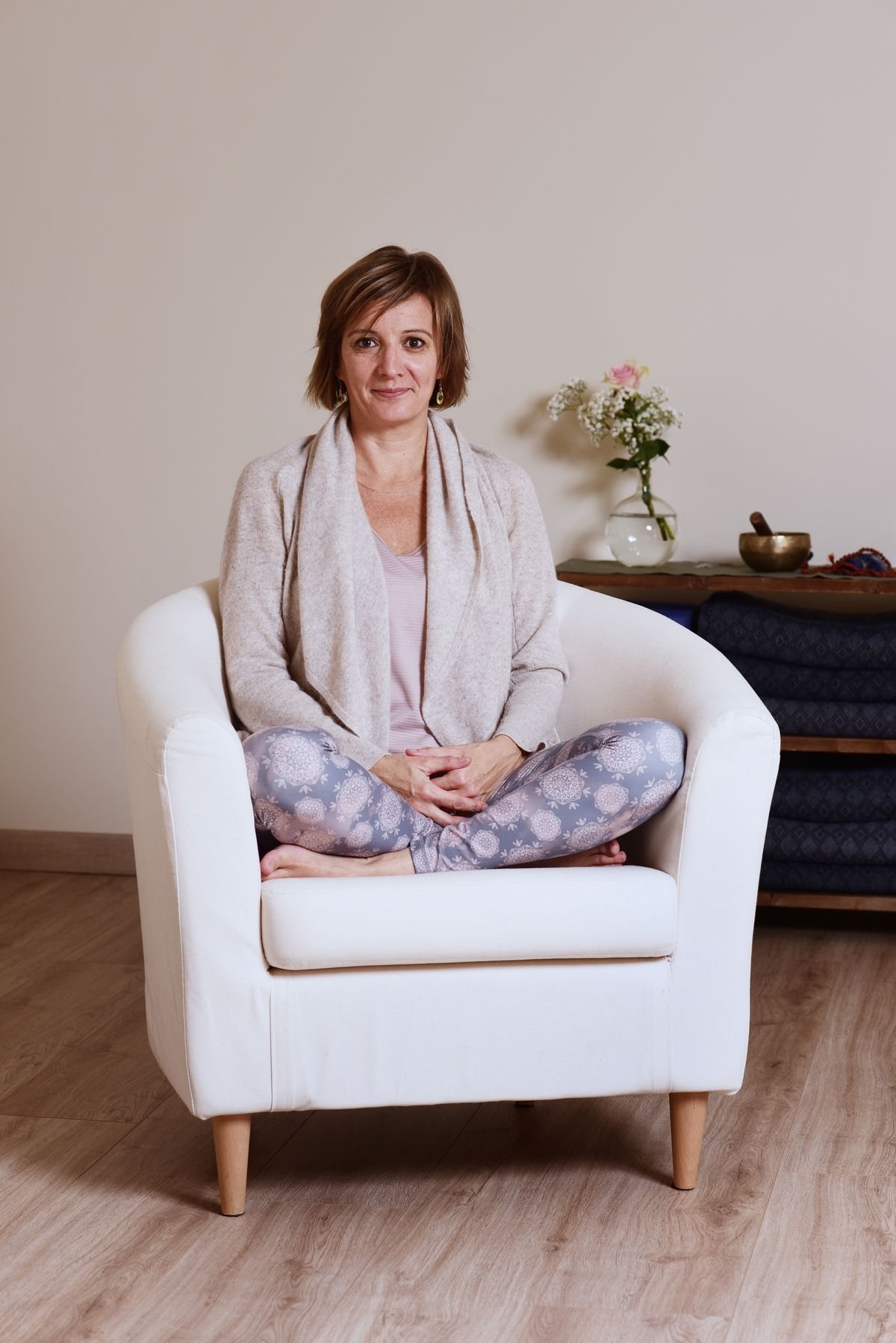 Audrey Favreau sitting cross-legged in a white armchair in her teaching space