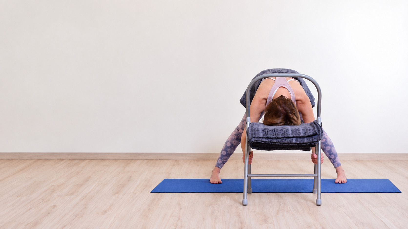 Audrey Favreau in a supported forward fold with a chair during a Restorative Yoga practice